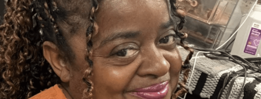 Smiling woman with braided hair indoors.